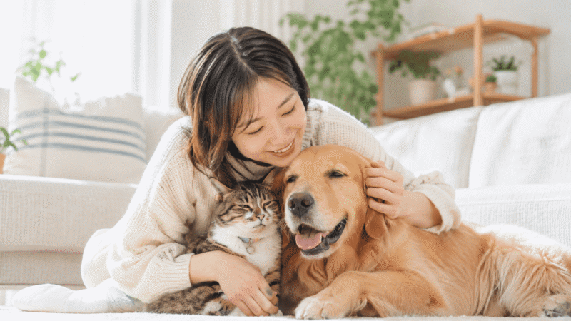 女性とゴールデンレトリバーと猫